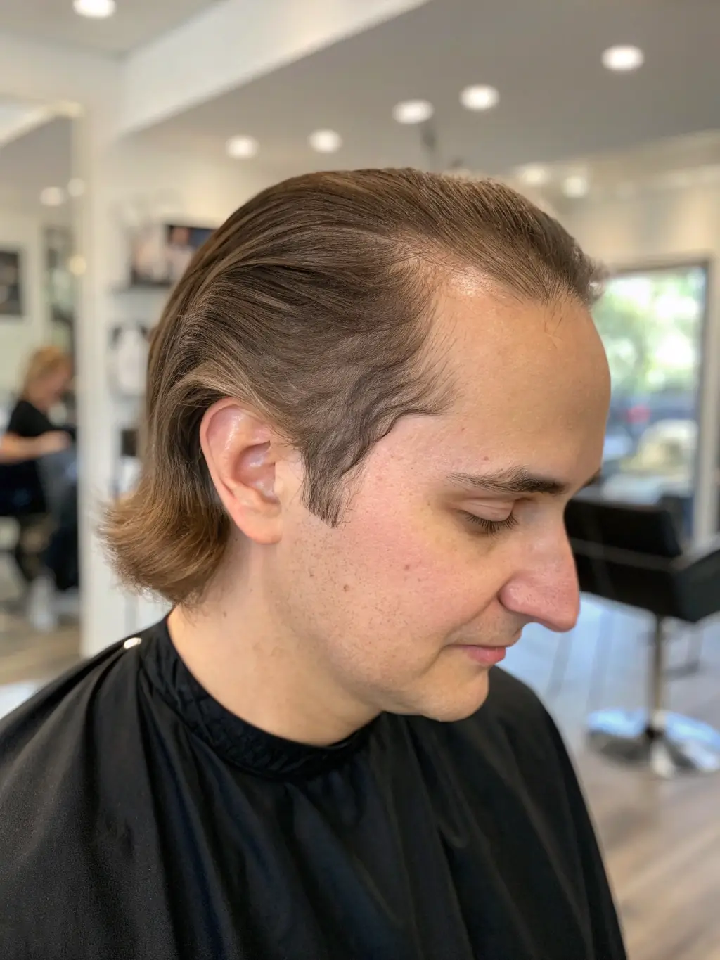 A close-up shot of a woman smiling confidently, showcasing a seamless mesh integration hair system that blends perfectly with her natural hair at The Collective Salon.
